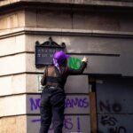 A woman protests in front of a marked wall during a demonstration in Mexico City.